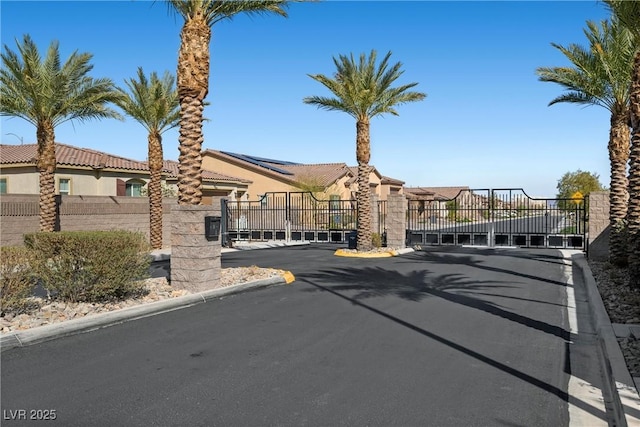 view of street featuring a gated entry, curbs, and a gate