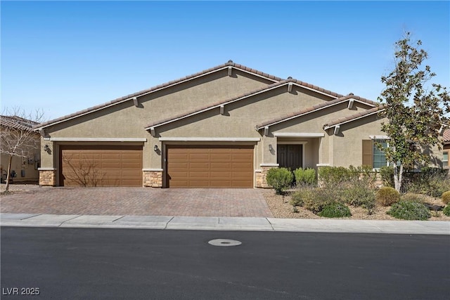 view of front of home featuring stucco siding, decorative driveway, stone siding, a garage, and a tiled roof