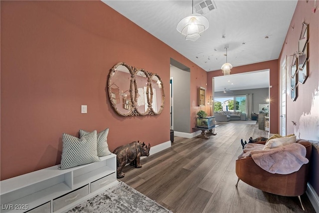 corridor featuring wood finished floors, visible vents, and baseboards