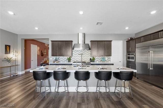 kitchen with visible vents, stainless steel appliances, wall chimney exhaust hood, and light countertops