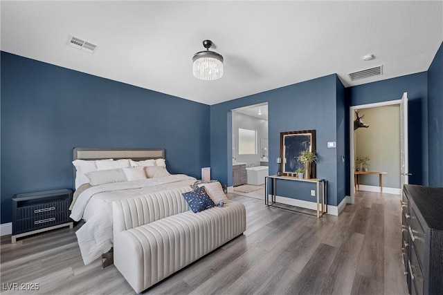 bedroom with a notable chandelier, wood finished floors, and visible vents