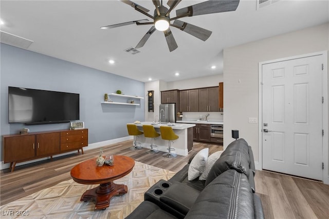 living area featuring visible vents, recessed lighting, light wood finished floors, baseboards, and ceiling fan