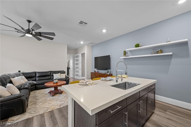 kitchen with a sink, light wood-type flooring, open floor plan, and light countertops