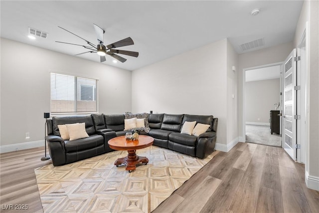 living area featuring light wood finished floors, visible vents, baseboards, and a ceiling fan