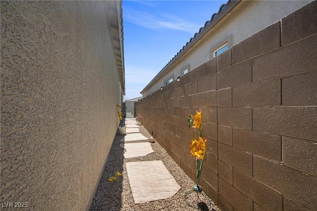 view of side of home featuring fence and stucco siding