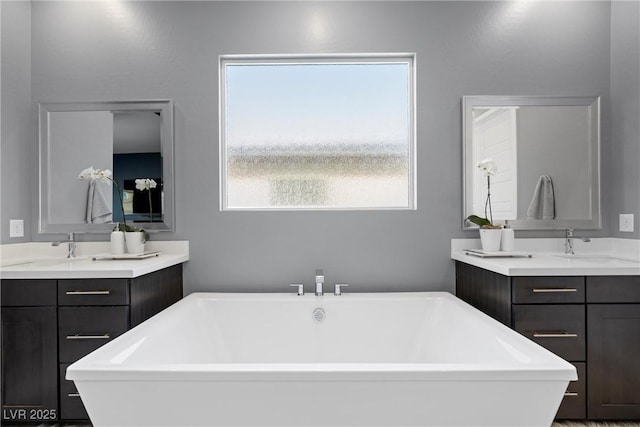 bathroom with a soaking tub, two vanities, and a sink