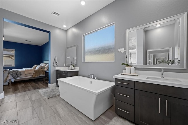 ensuite bathroom with visible vents, two vanities, a freestanding bath, a sink, and ensuite bathroom