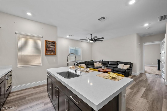 kitchen featuring visible vents, light wood-style flooring, light countertops, and a sink