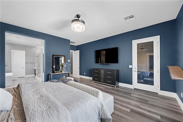 bedroom featuring wood finished floors, baseboards, visible vents, and connected bathroom