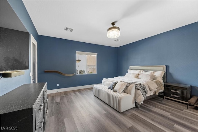 bedroom featuring visible vents, baseboards, and wood finished floors