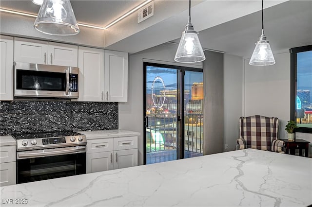 205 E Harmon Ave Unit 1010, Las Vegas, NV 89169 - kitchen featuring tasteful backsplash, visible vents, white cabinets, appliances with stainless steel finishes, and light stone counters