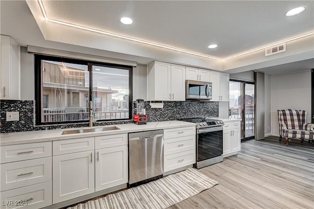 205 E Harmon Ave Unit 1010, Las Vegas, NV 89169 - kitchen featuring visible vents, white cabinets, a sink, stainless steel appliances, and light wood finished floors