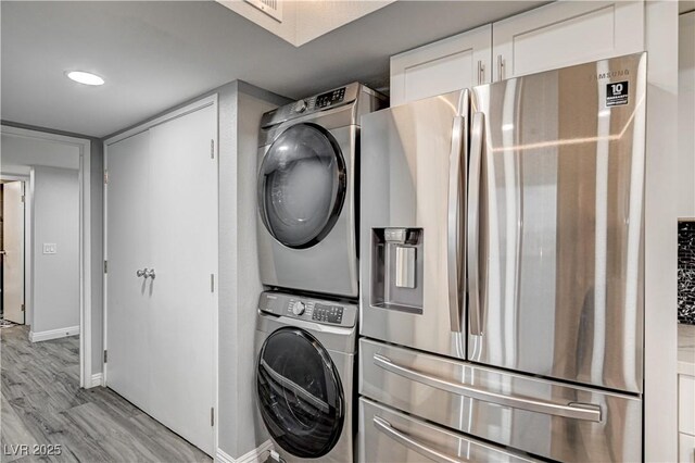 205 E Harmon Ave Unit 1010, Las Vegas, NV 89169 - clothes washing area with visible vents, baseboards, laundry area, stacked washer and dryer, and light wood-style flooring