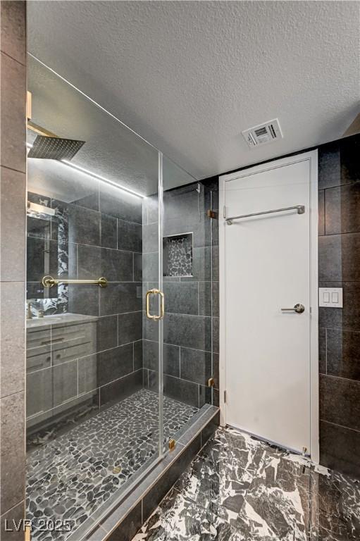 205 E Harmon Ave Unit 1010, Las Vegas, NV 89169 - full bathroom with vanity, a textured ceiling, a shower stall, visible vents, and marble finish floor