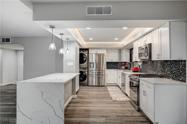 205 E Harmon Ave Unit 1010, Las Vegas, NV 89169 - kitchen with stacked washer / dryer, a tray ceiling, visible vents, and stainless steel appliances