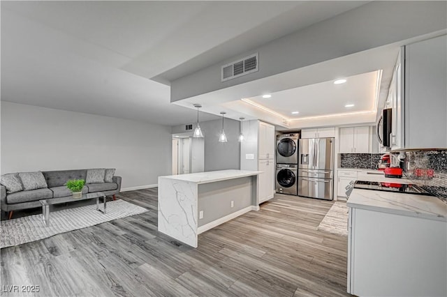 205 E Harmon Ave Unit 1010, Las Vegas, NV 89169 - kitchen featuring light stone countertops, stacked washer / dryer, visible vents, a raised ceiling, and appliances with stainless steel finishes