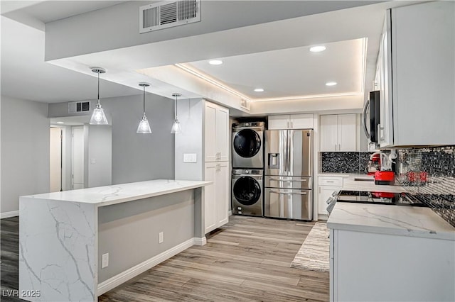 205 E Harmon Ave Unit 1010, Las Vegas, NV 89169 - kitchen with visible vents, light wood-type flooring, appliances with stainless steel finishes, and stacked washer / dryer