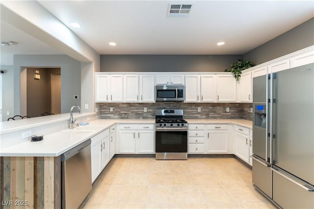 kitchen with visible vents, a sink, white cabinets, appliances with stainless steel finishes, and backsplash