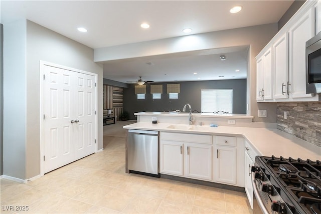 kitchen with a ceiling fan, a sink, a peninsula, appliances with stainless steel finishes, and white cabinets