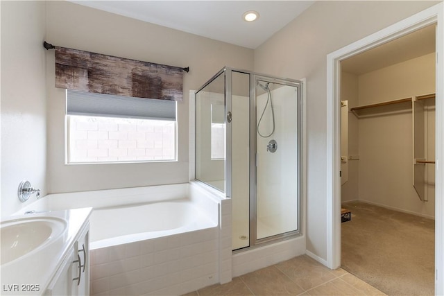 bathroom with a garden tub, a spacious closet, a stall shower, and tile patterned floors