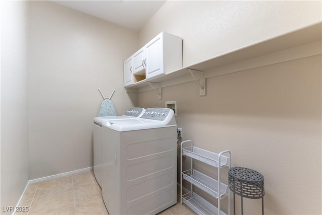 clothes washing area with baseboards, cabinet space, light tile patterned flooring, and washing machine and clothes dryer