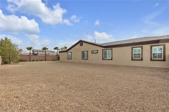 back of property featuring fence and stucco siding