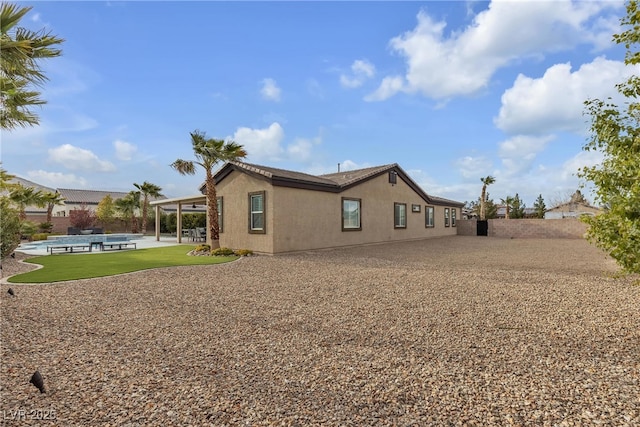 rear view of property featuring a patio, an outdoor pool, and stucco siding