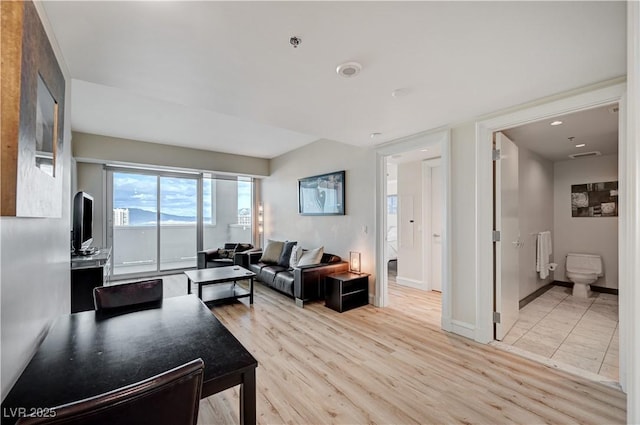 living room featuring visible vents, baseboards, radiator, and light wood finished floors