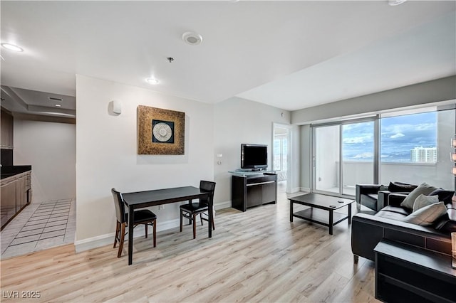 living area featuring recessed lighting, baseboards, and light wood-type flooring