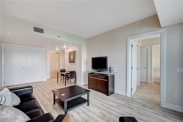 living area with visible vents, light wood-type flooring, and baseboards