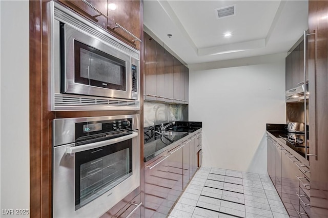 kitchen with visible vents, a sink, stainless steel appliances, a raised ceiling, and modern cabinets