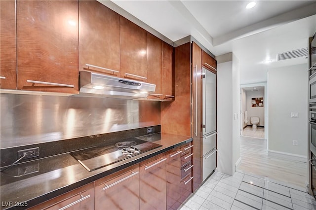 kitchen featuring visible vents, under cabinet range hood, dark countertops, light tile patterned flooring, and black electric cooktop