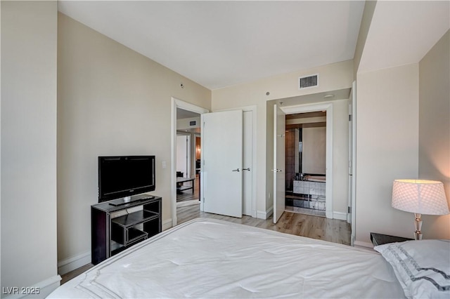 bedroom with wood finished floors, visible vents, and baseboards