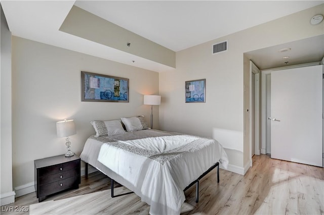 bedroom with baseboards, visible vents, and light wood-type flooring