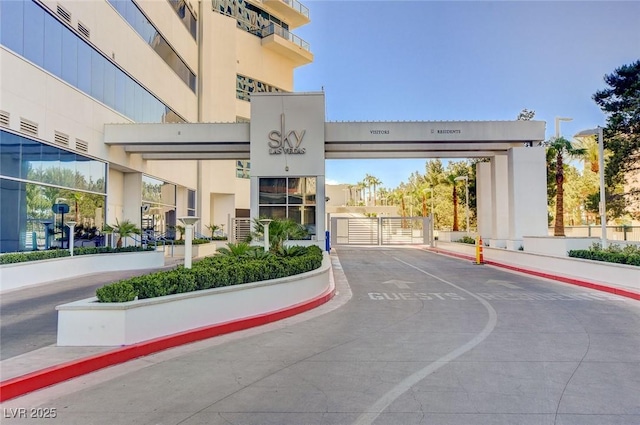 view of street with curbs, a gated entry, and sidewalks