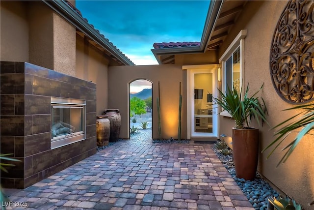 property entrance with a patio, a tiled roof, and stucco siding