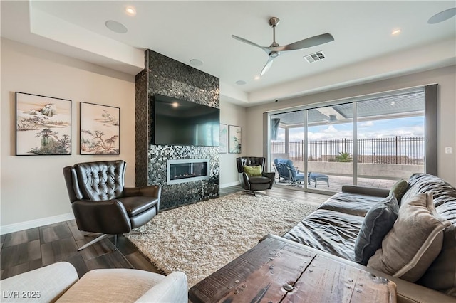 living room with visible vents, wood finished floors, baseboards, and ceiling fan