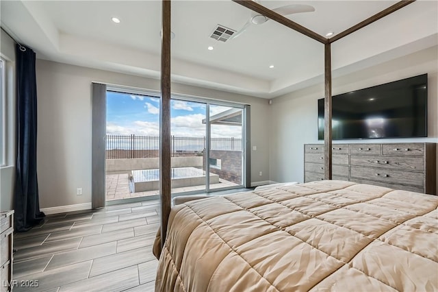 bedroom with a tray ceiling, visible vents, baseboards, and access to outside