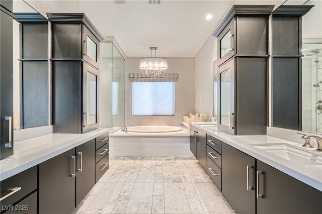 bathroom with visible vents, a chandelier, vanity, and a bath