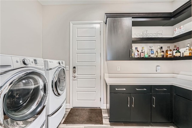 clothes washing area with cabinet space, a bar, and independent washer and dryer