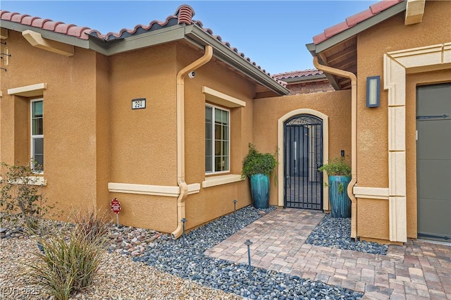 view of exterior entry featuring a tiled roof and stucco siding