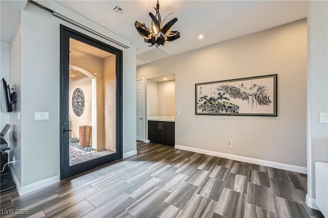 interior space with visible vents, baseboards, a notable chandelier, and wood tiled floor