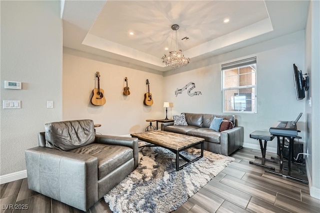 living room with a tray ceiling, a chandelier, and wood tiled floor