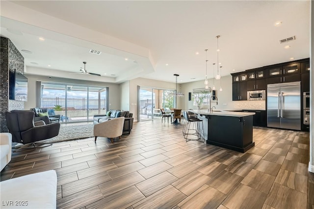 interior space with light countertops, visible vents, open floor plan, and built in appliances