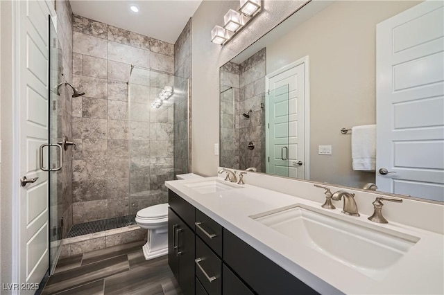 bathroom with a sink, toilet, double vanity, and a shower stall