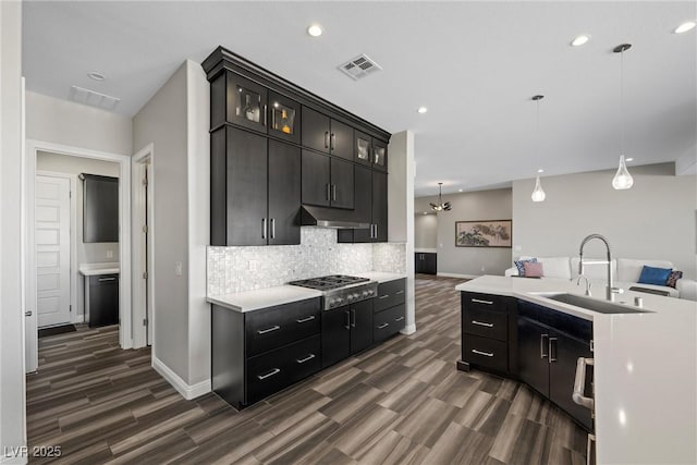 294 Besame Ct, Las Vegas, NV 89138 - kitchen with decorative backsplash, visible vents, a sink, under cabinet range hood, and dark wood-type flooring