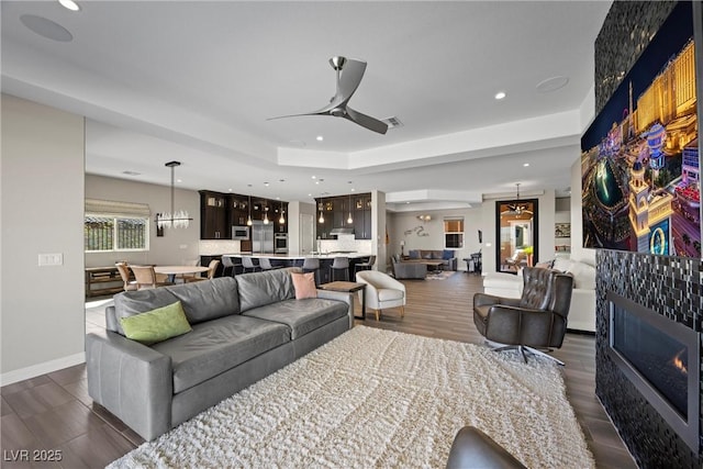 294 Besame Ct, Las Vegas, NV 89138 - living room featuring a glass covered fireplace, recessed lighting, dark wood-type flooring, a tray ceiling, and a ceiling fan