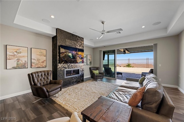 294 Besame Ct, Las Vegas, NV 89138 - living room with wood finished floors, baseboards, a raised ceiling, a tiled fireplace, and a ceiling fan