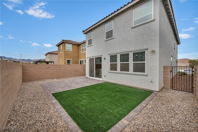 rear view of house with a patio, a fenced backyard, a tile roof, and stucco siding