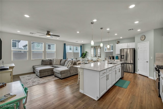 kitchen with a sink, stainless steel appliances, visible vents, and wood finished floors